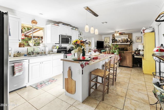 kitchen featuring a center island, crown molding, decorative light fixtures, white cabinetry, and stainless steel appliances