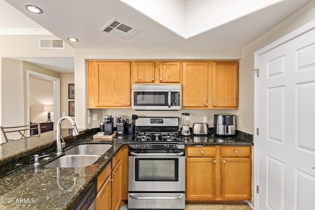 kitchen featuring visible vents, appliances with stainless steel finishes, dark stone counters, and a sink