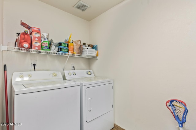 clothes washing area with laundry area, visible vents, and separate washer and dryer