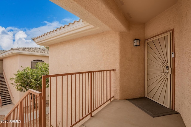 property entrance featuring a tiled roof, a balcony, and stucco siding