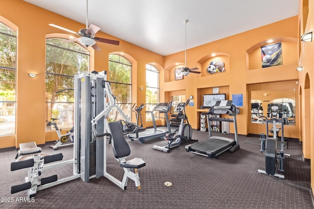 exercise room with a towering ceiling and ceiling fan