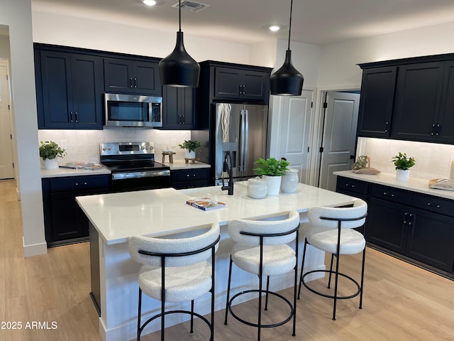 kitchen with a kitchen bar, a center island with sink, and appliances with stainless steel finishes