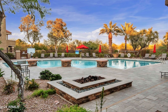 view of pool with a patio area, pool water feature, and a fire pit