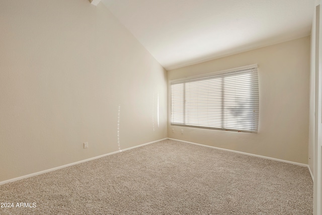 carpeted empty room featuring lofted ceiling