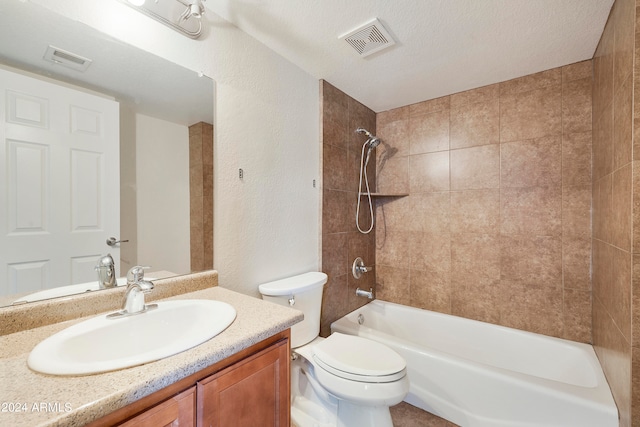 full bathroom featuring a textured ceiling, vanity, toilet, and tiled shower / bath