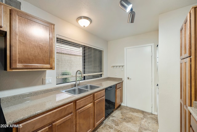 kitchen featuring black dishwasher, sink, and light stone counters