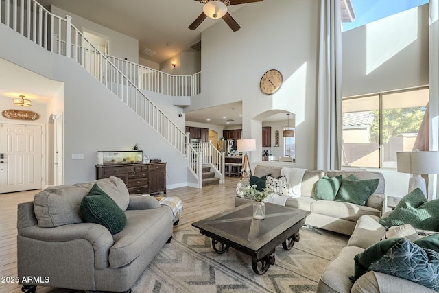 living room featuring ceiling fan, light hardwood / wood-style floors, and a high ceiling