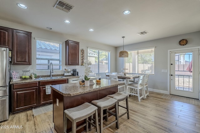 kitchen featuring a center island, decorative light fixtures, sink, light wood-type flooring, and a breakfast bar area