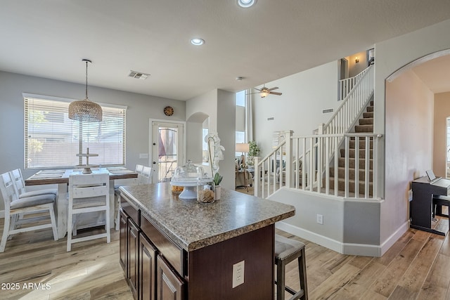 kitchen with light hardwood / wood-style floors, dark brown cabinets, ceiling fan, and a kitchen island