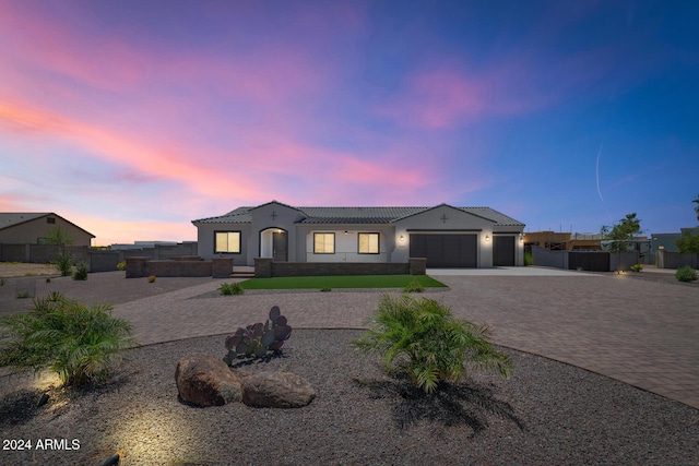 view of front of house with a garage, a tile roof, fence, decorative driveway, and stucco siding