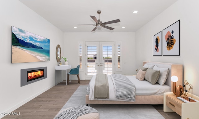 bedroom featuring access to exterior, recessed lighting, french doors, and a glass covered fireplace