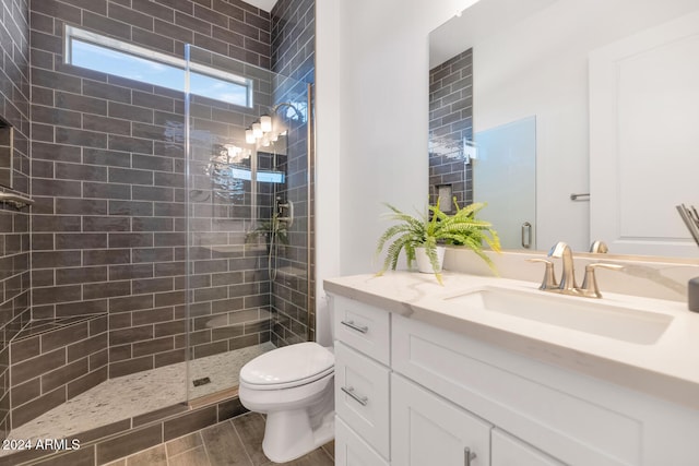 bathroom with toilet, a tile shower, and vanity