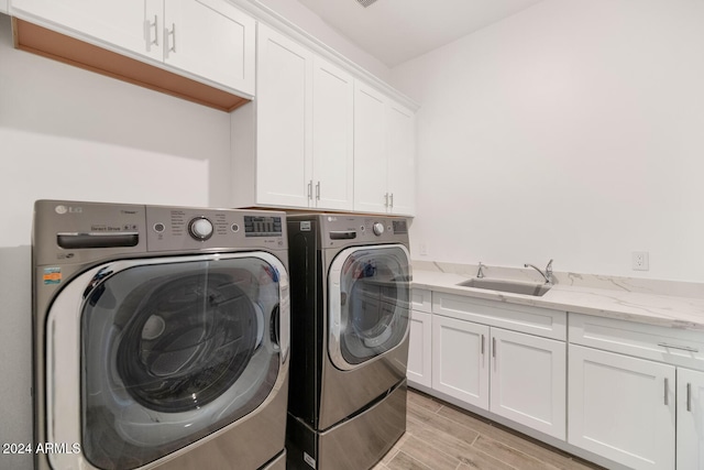 clothes washing area with wood finish floors, a sink, cabinet space, and washer and dryer