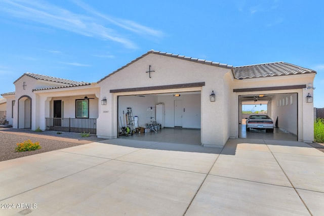 mediterranean / spanish-style home featuring a garage, concrete driveway, a tile roof, a porch, and stucco siding