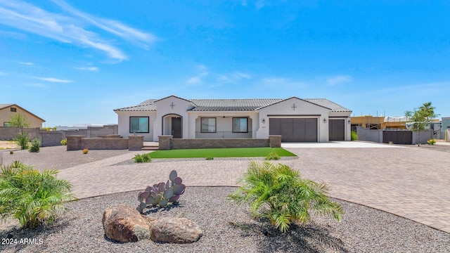 view of front facade featuring an attached garage, fence, a tiled roof, decorative driveway, and stucco siding