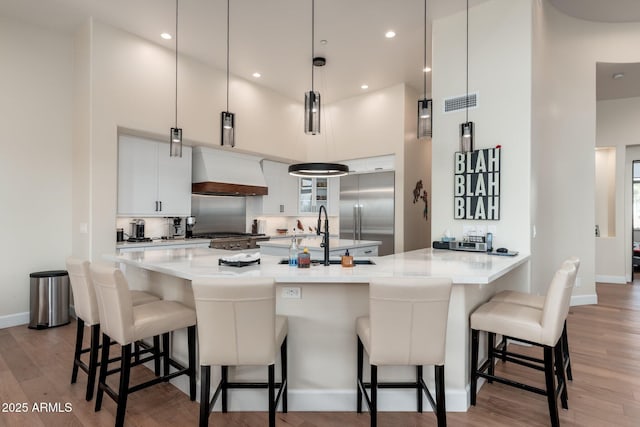 28768 N 95th Way, Scottsdale, AZ 85262 - kitchen with custom range hood, high quality fridge, light wood-type flooring, a kitchen breakfast bar, and light countertops