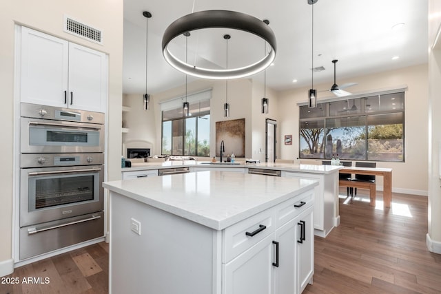 28768 N 95th Way, Scottsdale, AZ 85262 - kitchen with a warming drawer, appliances with stainless steel finishes, a center island, a peninsula, and wood finished floors