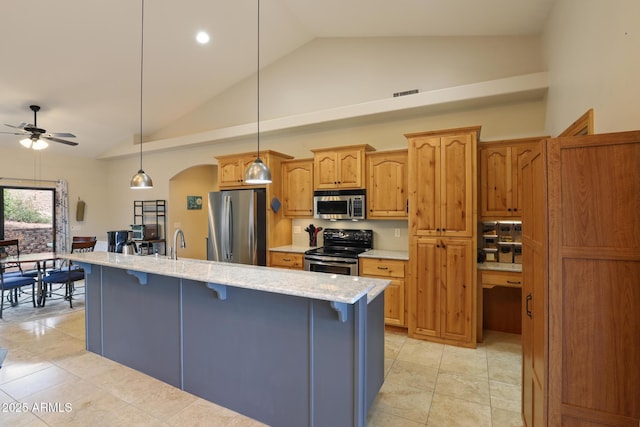 kitchen featuring a ceiling fan, appliances with stainless steel finishes, arched walkways, and a breakfast bar area