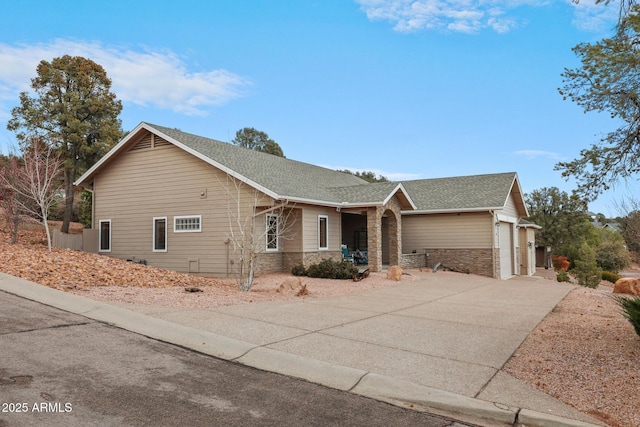 ranch-style home featuring stone siding, roof with shingles, an attached garage, and driveway