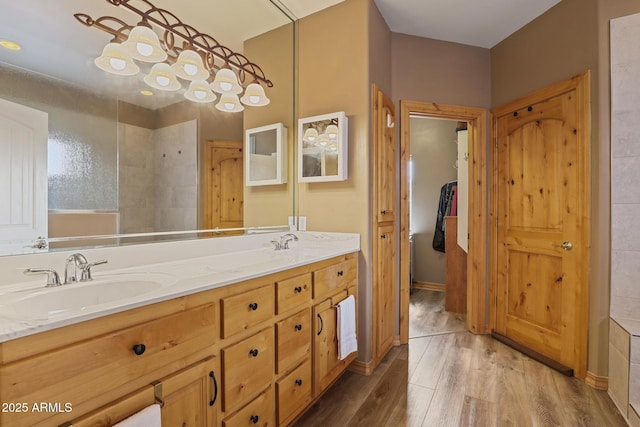 full bath featuring double vanity, wood finished floors, and a sink