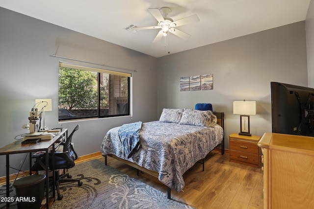 bedroom featuring a ceiling fan, wood finished floors, visible vents, and baseboards