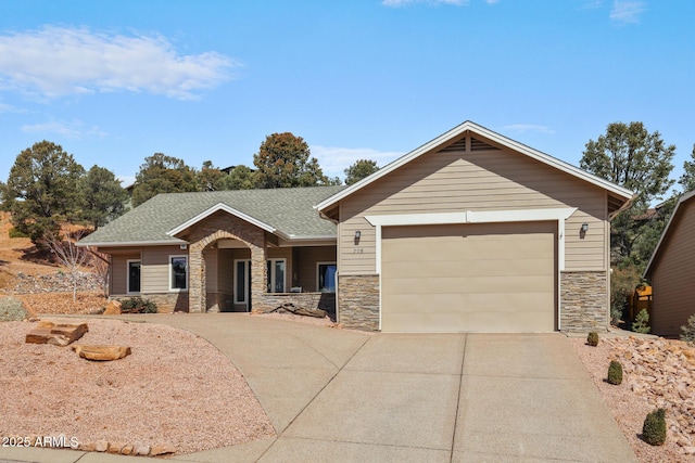 view of front facade with an attached garage, stone siding, a shingled roof, and concrete driveway