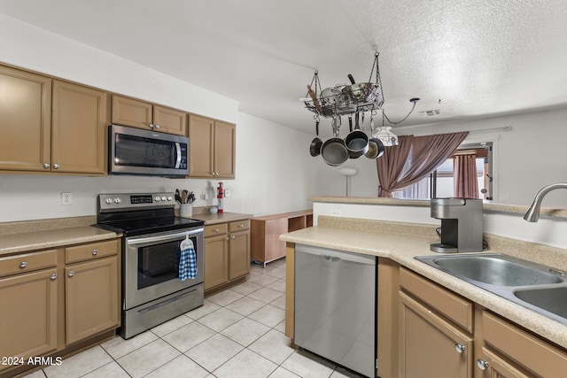 kitchen with sink, light tile patterned flooring, stainless steel appliances, and a textured ceiling