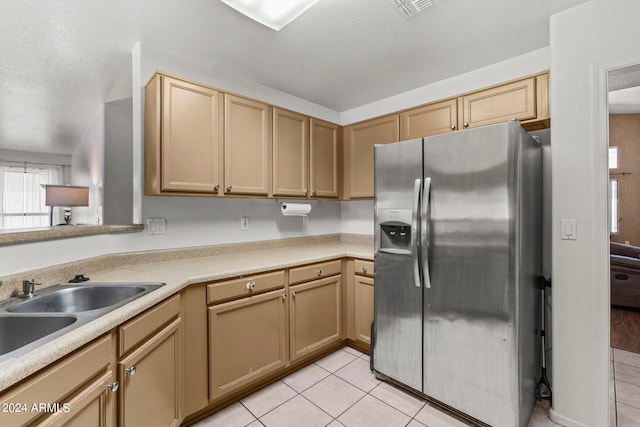 kitchen featuring stainless steel fridge with ice dispenser, sink, light tile patterned flooring, and a textured ceiling