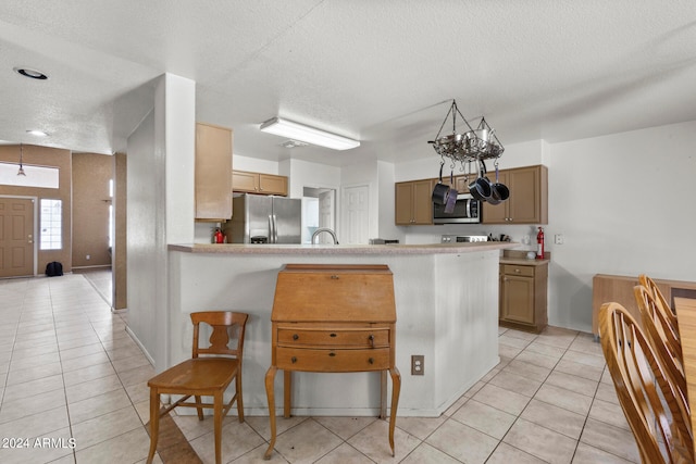 kitchen with a textured ceiling, kitchen peninsula, a breakfast bar area, and appliances with stainless steel finishes