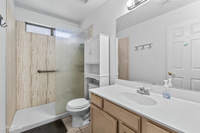 bathroom with tile patterned flooring, vanity, toilet, and a shower