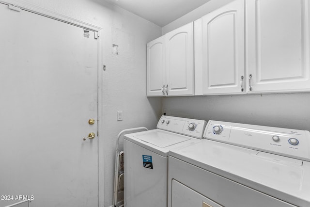 clothes washing area featuring washer and clothes dryer and cabinets