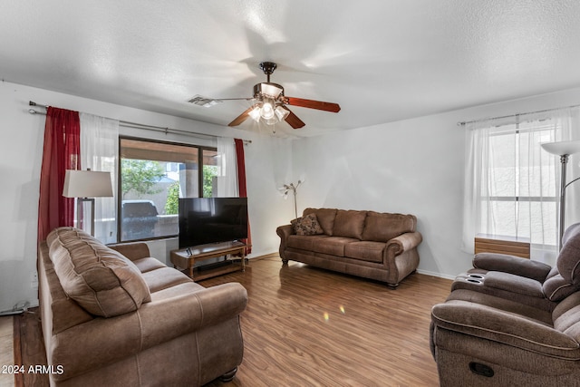 living room with a textured ceiling, hardwood / wood-style flooring, and ceiling fan