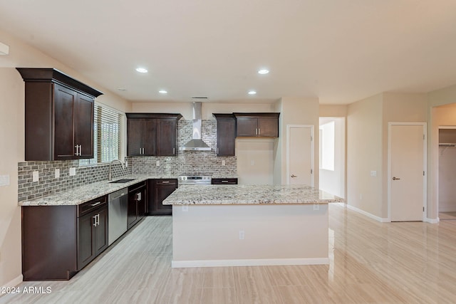 kitchen featuring light stone counters, a kitchen island, wall chimney range hood, and stainless steel appliances