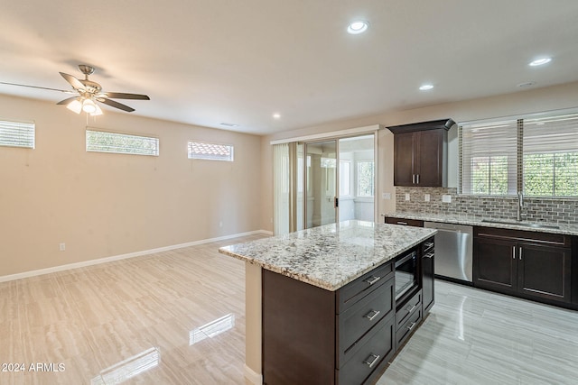 kitchen featuring decorative backsplash, ceiling fan, appliances with stainless steel finishes, a kitchen island, and sink