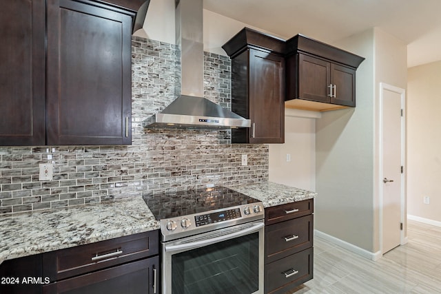 kitchen featuring wall chimney range hood, dark brown cabinets, tasteful backsplash, and stainless steel electric range