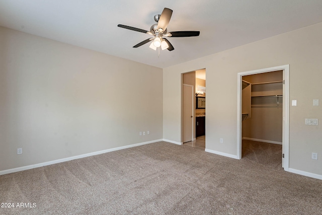 unfurnished bedroom featuring a spacious closet, ceiling fan, a closet, and light carpet