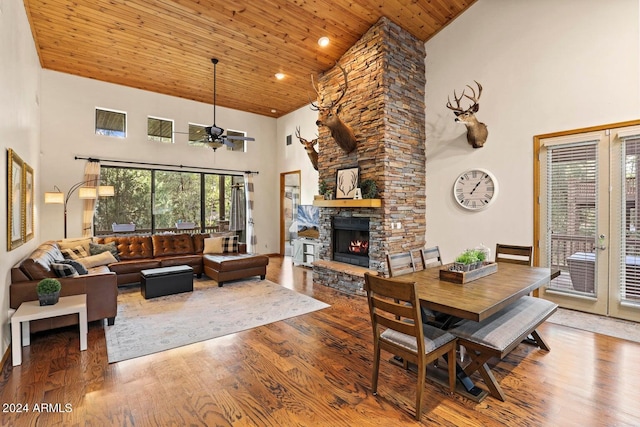 dining area featuring a stone fireplace, hardwood / wood-style floors, high vaulted ceiling, wooden ceiling, and french doors