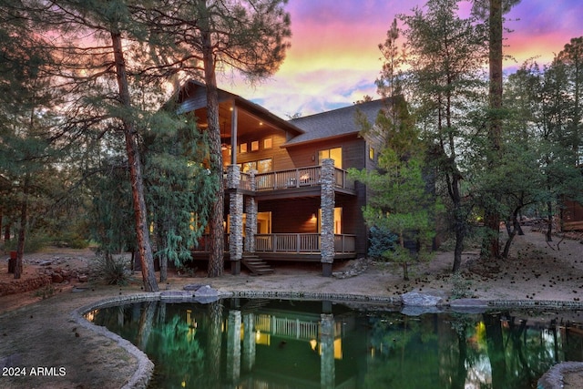 back house at dusk featuring a balcony