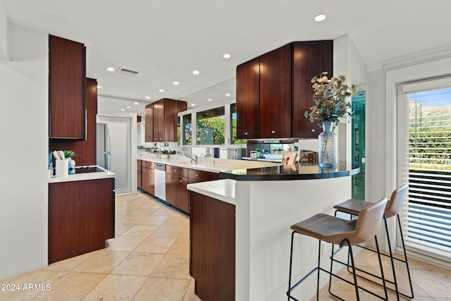 kitchen featuring kitchen peninsula, appliances with stainless steel finishes, light tile patterned floors, and a breakfast bar area