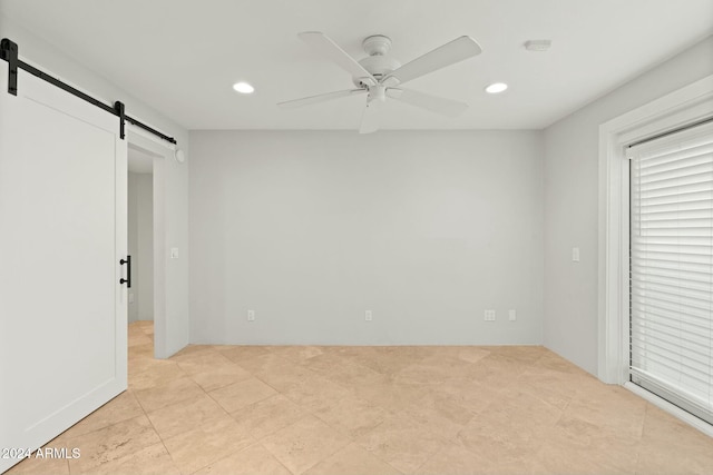 unfurnished bedroom with a barn door and ceiling fan