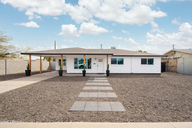 ranch-style home with a carport, a porch, concrete driveway, and fence