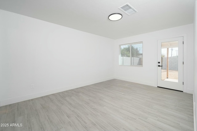 spare room with light wood-style floors, visible vents, and baseboards