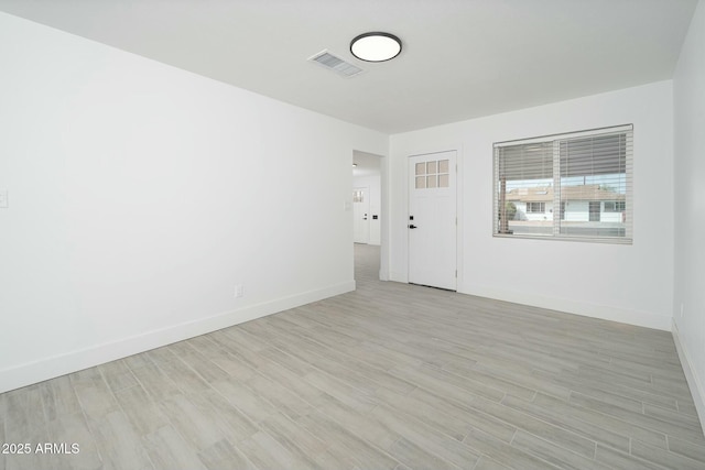 empty room with baseboards, visible vents, and light wood-style floors