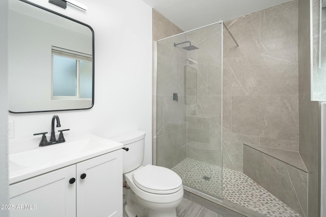 bathroom featuring a tile shower, vanity, and toilet