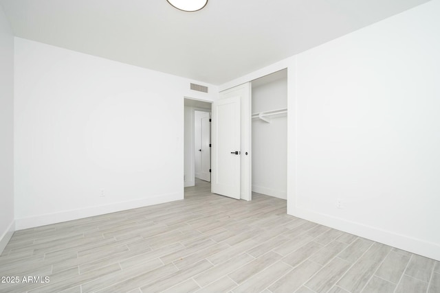 unfurnished bedroom featuring baseboards, visible vents, a closet, and wood finish floors