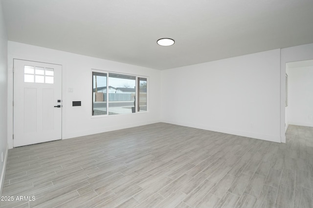 interior space featuring light wood finished floors, baseboards, and a wealth of natural light