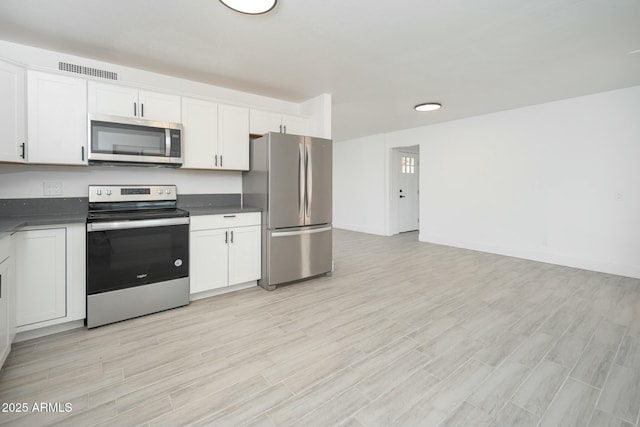 kitchen featuring light wood-style flooring, visible vents, white cabinetry, appliances with stainless steel finishes, and dark countertops