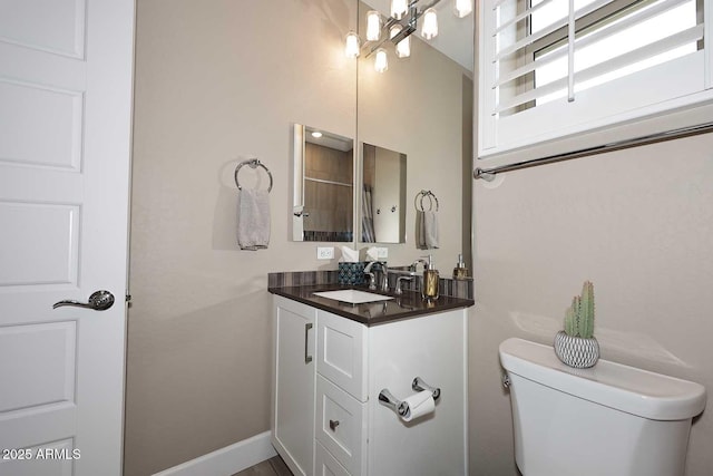 bathroom with vanity, an inviting chandelier, toilet, and baseboards