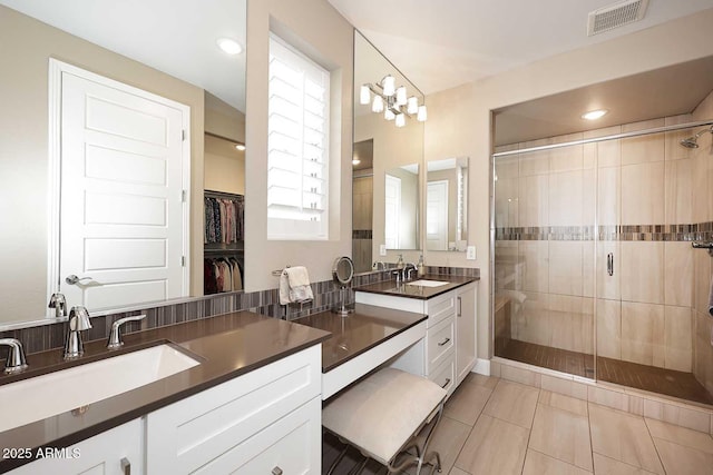 bathroom with a shower stall, double vanity, visible vents, and a sink