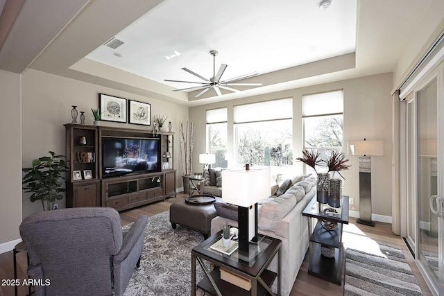 living area featuring visible vents, a raised ceiling, a ceiling fan, and wood finished floors